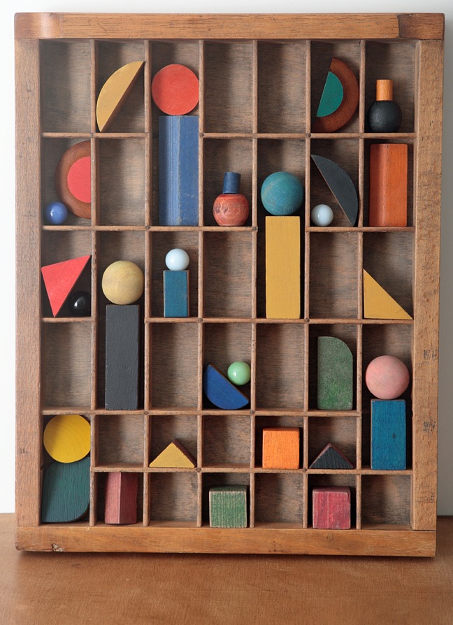 Assemblage artwork of old wooden blocks in an vintage letterpress printers type case drawer tray 