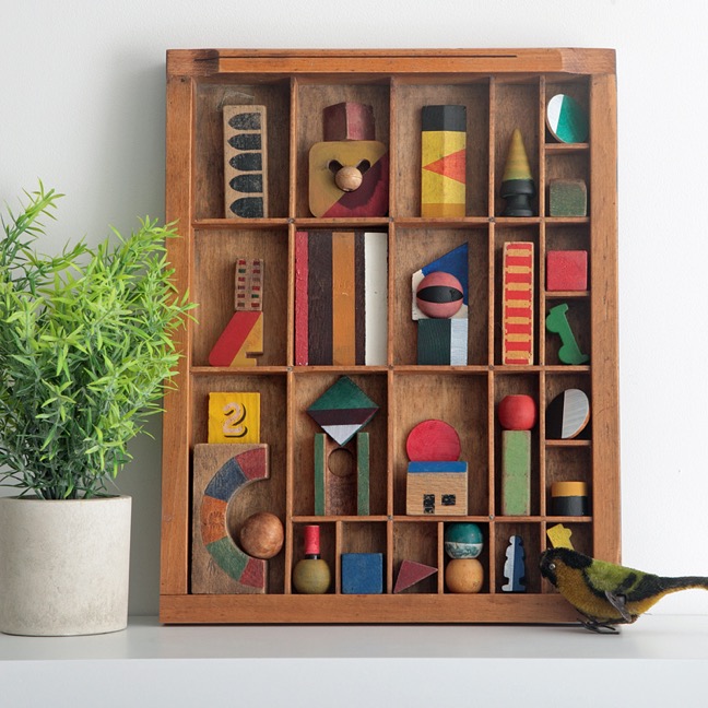 Assemblage artwork of old wooden blocks in an vintage letterpress printers type case drawer tray 