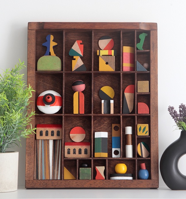 Assemblage artwork of old wooden blocks in an vintage letterpress printers type case drawer tray 