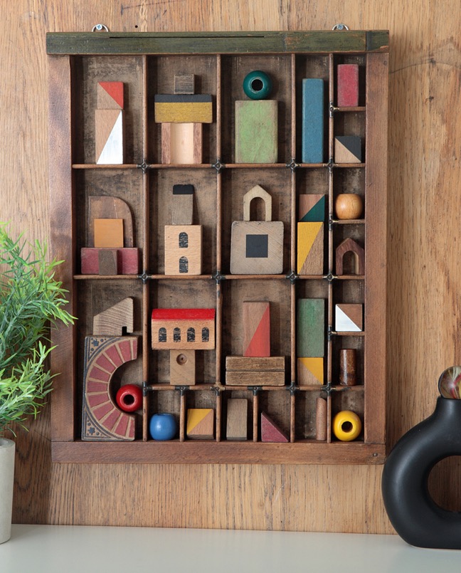 Assemblage artwork of old wooden blocks in an vintage letterpress printers type case drawer tray 