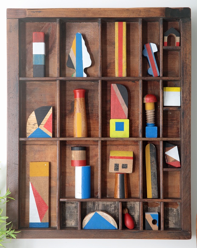 Assemblage artwork of old wooden blocks in an vintage letterpress printers type case drawer tray 