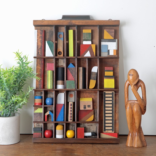 Assemblage artwork of old wooden blocks in an vintage letterpress printers type case drawer tray 